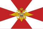 Flag of Internal Troops: a 2:3 white flag with rose madder cross pattée and emblem of Internal Troops in the center of it[2]