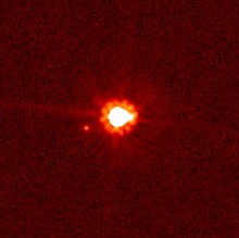 Image rougeâtre où un gros point blanc est situé à côté d'un autre petit point rouge.