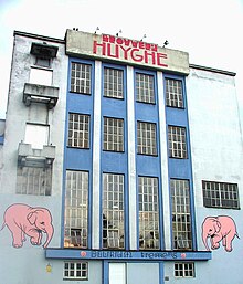 Photographie en couleurs de la façade blanche d'une brasserie, ornée de deux éléphants roses.