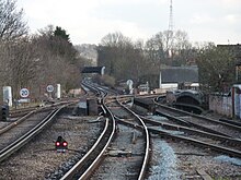 A pair of third-rail railway tracks are intersected by a second pair of tracks coming in from the right