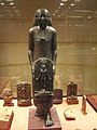 Statue of individual holding a stele: a Cippus of Horus healing statue