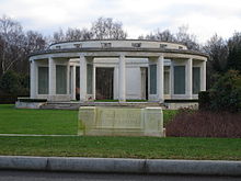 Open white stone circular structure, supported by broad columns carrying inscribed tablets