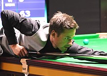 David Gilbert lining up a shot while leaning over a table