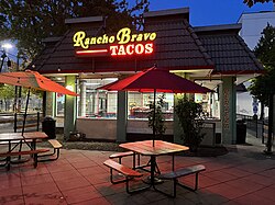 Photograph of a restaurant exterior with outdoor seating in the foreground