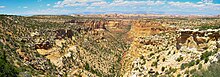 Panorama of a desert landscape with a canyon running through the center of the picture.