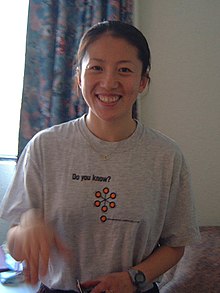 Photographie d'une femme souriante en t-shirt gris.