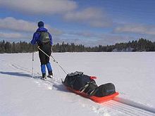 Uno sciatore di fondo in Finlandia che tira uno slittino di salvataggio con un bagaglio all'aperto.