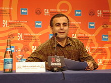 Photograph of Bahman Ghobadi sitting at a table in front of a microphone