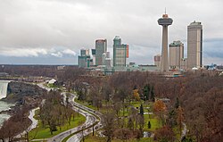 The skyline of Niagara Falls near the edge of the Horseshoe Falls (at left), including the Skylon Tower, the Fallsview Casino, and several high-rise hotels