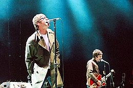 Oasis performing onstage, singing into microphones