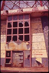 An abandoned entrance building to the abandoned Parachute Jump, seen in 1973. Several windows are broken and the paint has started to peel.