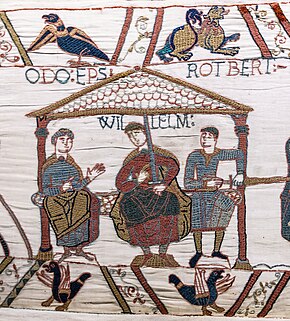 An embroidered cloth depicting three men sitting on a bench