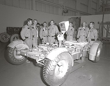(from left to right) Astronauts John Young, Eugene Cernan, Charles Duke, Fred Haise, Anthony England, Charles Fullerton, and Donald Peterson await deployment tests of the Lunar Roving Vehicle (LRV) qualification test unit in building 4649 at the Marshall Space Flight Center (MSFC). November 1971.