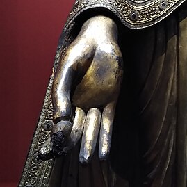Hand of a standing Buddha statue holding a myrobalan