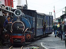 A photograph of the engine and several cars of the Darjeeling Himalayan Railway with people on either side of it