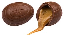 Two chocolate eggs, one split open with caramel filling spilling out