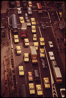 Aerial view of the Herald Square area of mid-town Manhattan, near the intersection of 34th Street and Broadway. Traffic is nearly gridlocked, as each of the five the lanes are filled by cars and trucks. Of the vehicles shown in the photograph, 16 are yellow-colored taxicabs, but only three of the those are Checker Model A11 taxicabs.