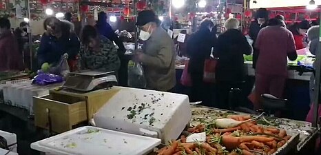 प्रकोप के दौरान 23 जनवरी को वुहान के निवासी बाजार में सब्जियों और अन्य भोजन सामान खरीदते हुए