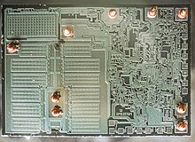 Die of LM2576T monolithic integrated circuits step−down switching regulator (buck converter) which contains 162 active transistors (based on datasheet). The Biggest part of die on the left side is Built-in 3 Ampere power transistor and the damaged and fried part of die is clearly visible as a small black in power transistor section.