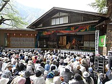 Photo couleur d'une foule de personnes assistant à une séance de kabuki.