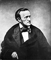 A photograph of the upper half of a man of about fifty viewed from his front right. He wears a cravat and frock coat. He has long sideburns and his dark hair is receding at the temples.