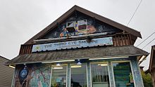 Photograph of a building's exterior, which is covered in colorful murals and has a sign displaying "The Third Eye Shoppe" in the center