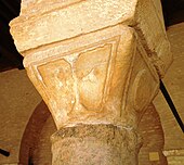 Photographie d'un chapiteau byzantin du portique oriental de la cour. Il est en forme de tronc de pyramide renversé à faces trapézoïdales, dont l'une portant une croix grecque.