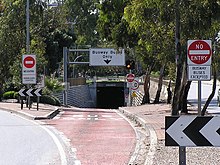 A road entering a tunnel with signs indicating the tunnel is for buses only