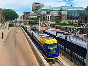 A Minneapolis-bound train (left) passes a Saint Paul-bound train (right) on the Green Line near East Bank station.