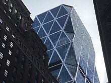 The facade of the Hearst Tower's upper stories as seen in August 2021. The facade is made of glass, with steel beams arranged in a triangle.