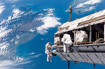 نشاط خارج محطَّة الفضاء الدوليَّة لدمج المحطَّة بمكّوك الفضاء STS-116 عن طريق رائديّ فضاء. يظهر في الخلفية مضيق كوك، في نيوزيلندا
