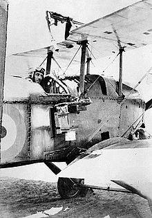Aviator in military biplane with camera mounted on fuselage