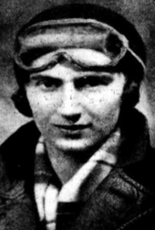 A black and white portrait photograph of a female racing driver in overalls