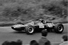Black-and-white photograph of Jochen Rindt racing in a wingless Cooper Formula One car with his name visibly written on the side of the car