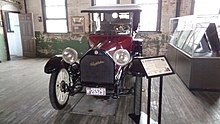 A red-colored, old-fashioned car with four seats and black-colored fittings