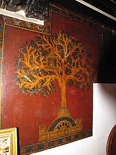 Artistic representation of the Kalpavriksha in Jainism. A wall painting of a tree on red backdrop.