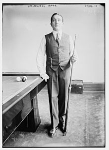 Melbourne Inman, wearing a waistcoat and carrying a billiard cue.