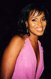 A woman with dark hair wearing a pink dress smiles