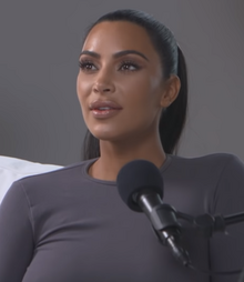 Kim Kardashian West looks to her right side with a microphone in front of her
