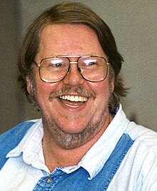 A headshot of a smiling man wearing glasses