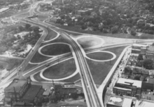 A four-lane highway and cloverleaf interchange, seen from above