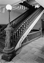Ornate cast iron staircase with a lamppost atop the newell