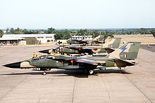 Side view of jets in two-tone green camouflage livery parked side by side on ramp.