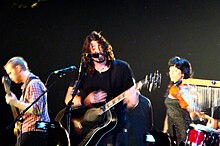 Una fotografia a colori di membri dei Foo Fighters in concerto