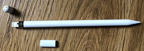 The first generation Apple Pencil, with its Lightning connector exposed. The accompanying female-to-female Lightning adapter is below the Pencil