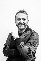 A black-and-white photograph of singer and songwriter Shane McAnally posing in front of the camera.