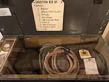 Uma caixa com cerca de 3 pés de comprimento, 1 pé de profundidade e 1 pé de largura, contendo todo o equipamento necessário para um carrasco, incluindo cordas, blocos e equipamentos, correias, etc.