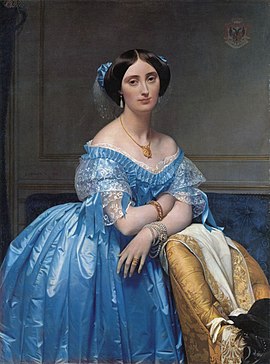 Pauline de Broglie is shown leaning against an upholstered chair. She wears a pale blue satin ball gown and lavish jewelry
