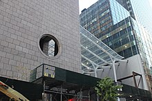 The northern facade of the building, looking west from 56th Street. There is a pink granite facade at left and a glass-roofed atrium at center.