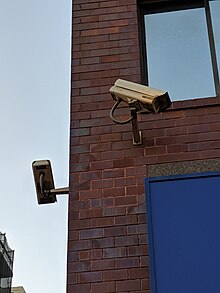 two CCTV cameras pointed in different directions mounted on the corner of a brick building